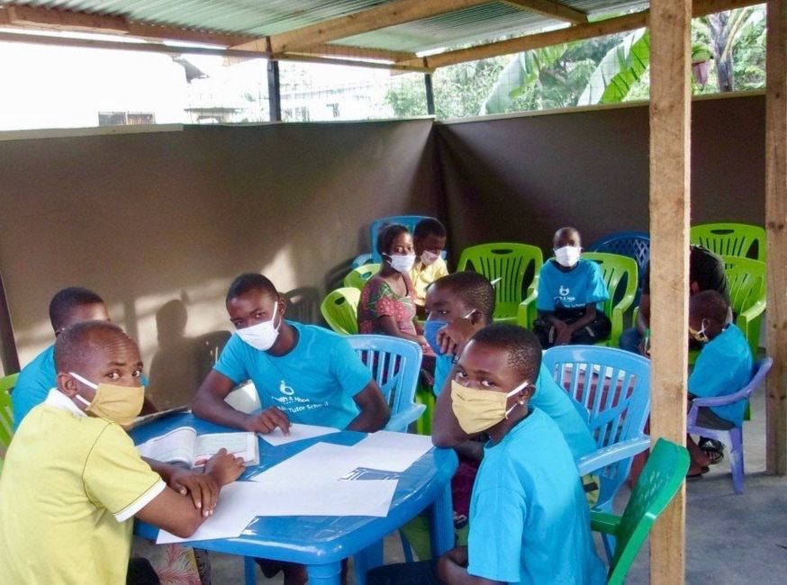 Students sitting around table studying and wearing masks.