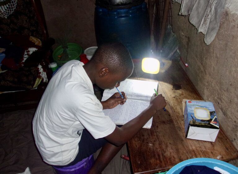 Boy doing his homework with a lamp.