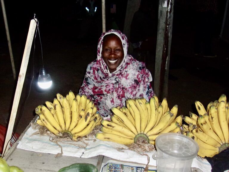 Woman sitting by a table with bananas.